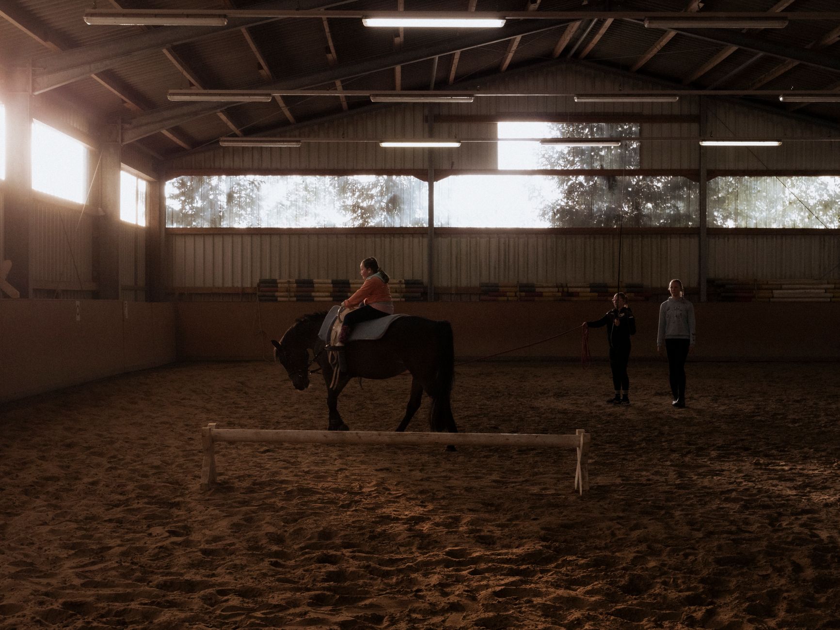 A riding instructor teaching in an indoor arena